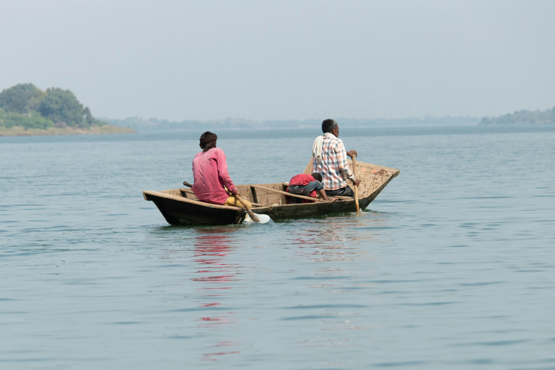 two men sitting in a canoe out in the ocean