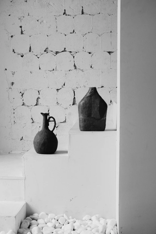 an arrangement of vases in front of a wall covered in rock