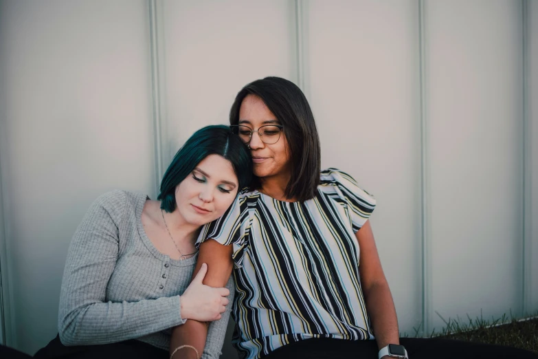 two women are sitting together on the ground