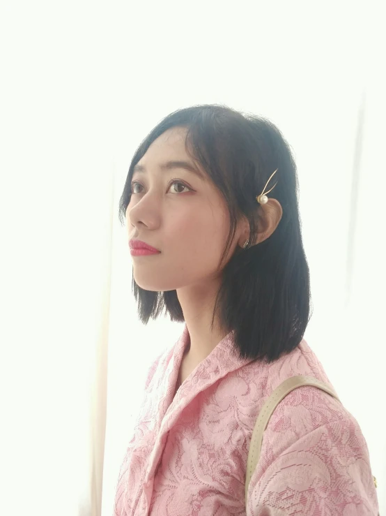 an asian woman wearing a pink blouse looking off to the side