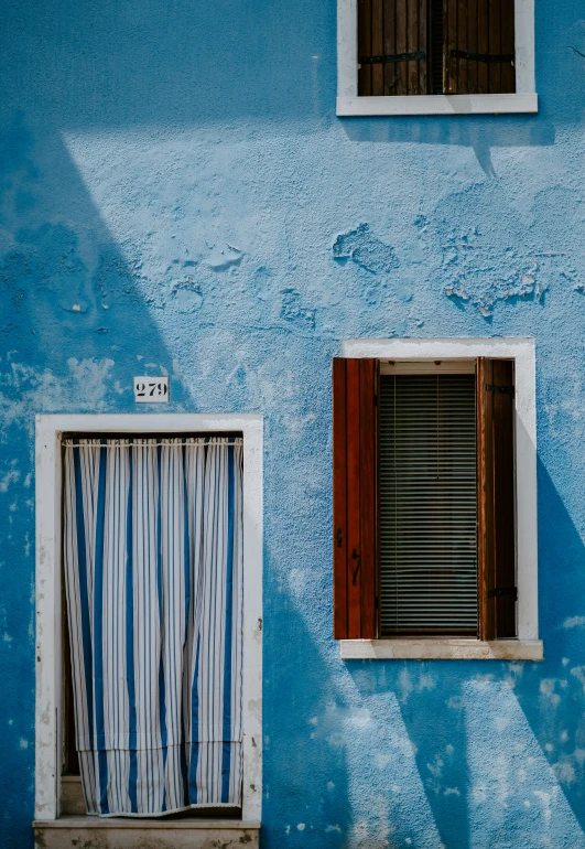 a window and curtain with the shades on blue wall