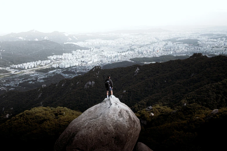 a lone person stands on top of a rocky peak