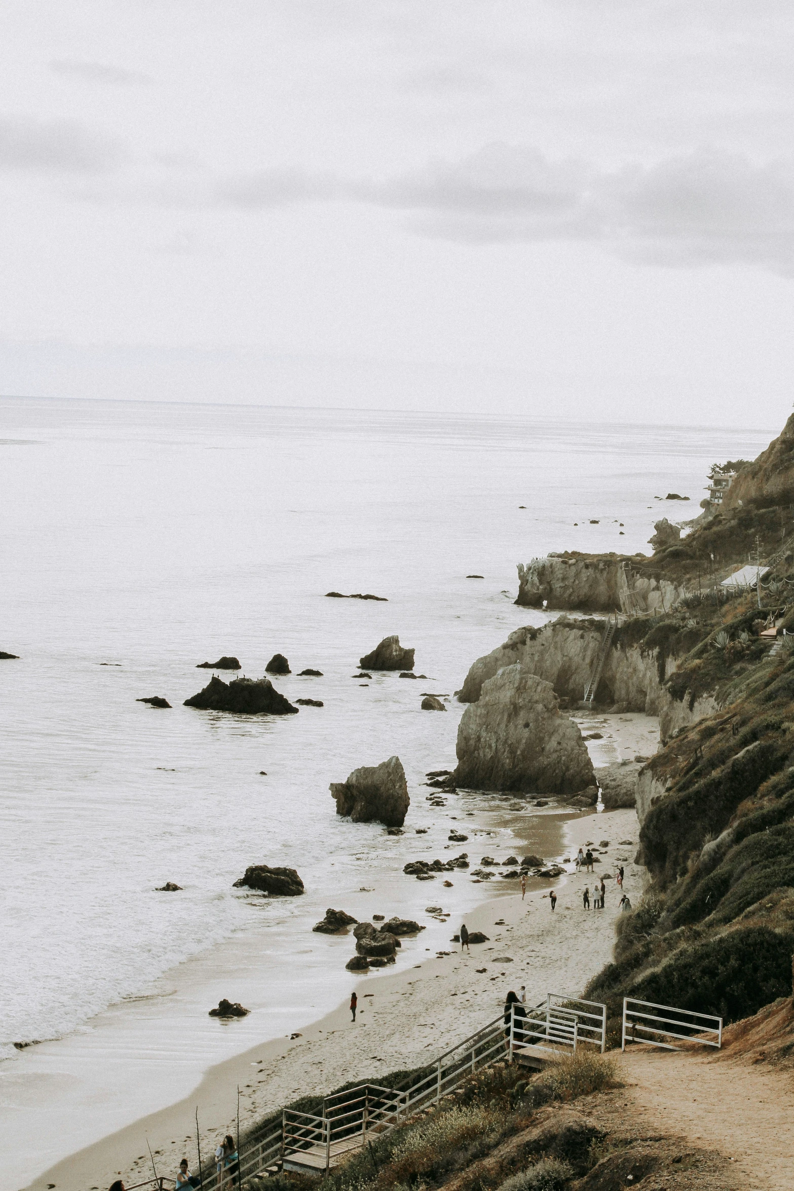 a cliff overlooking the beach next to a body of water