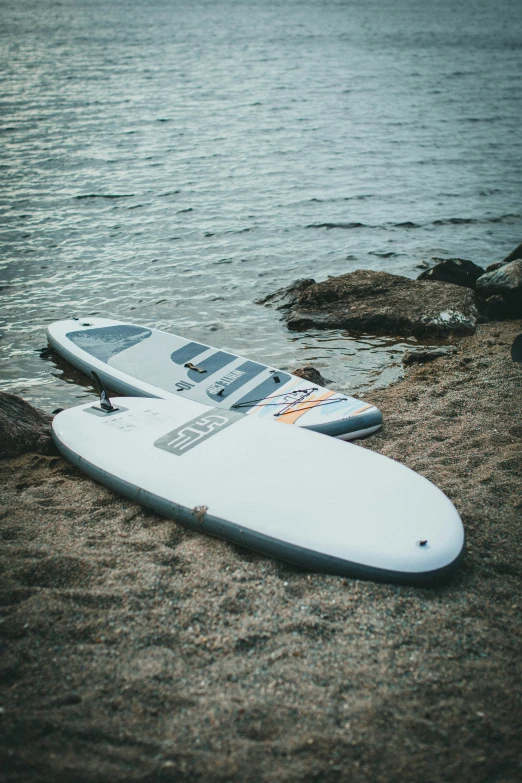 the surfboard is lying on a rock next to the water