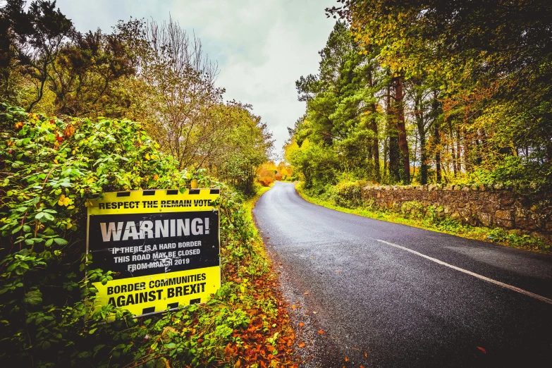 a sign near a country road with a warning ahead