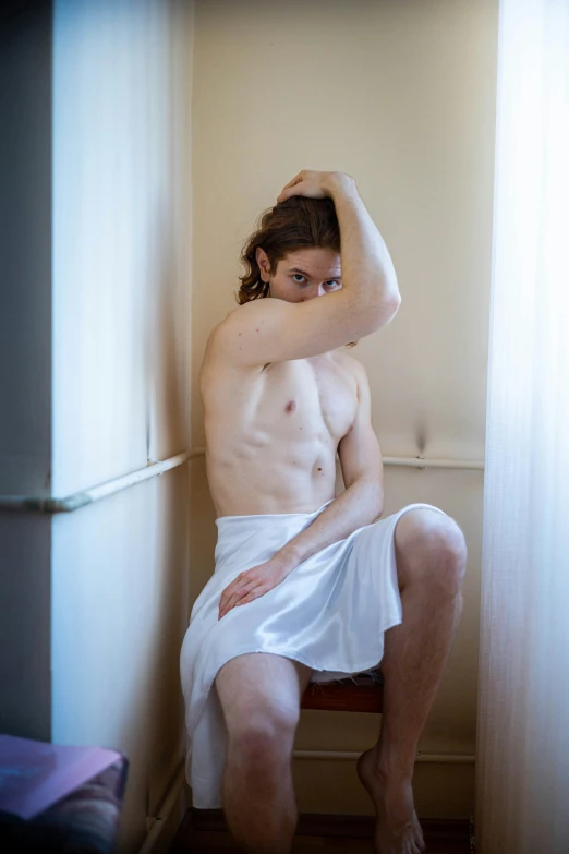 a young man with  is sitting on a step stool