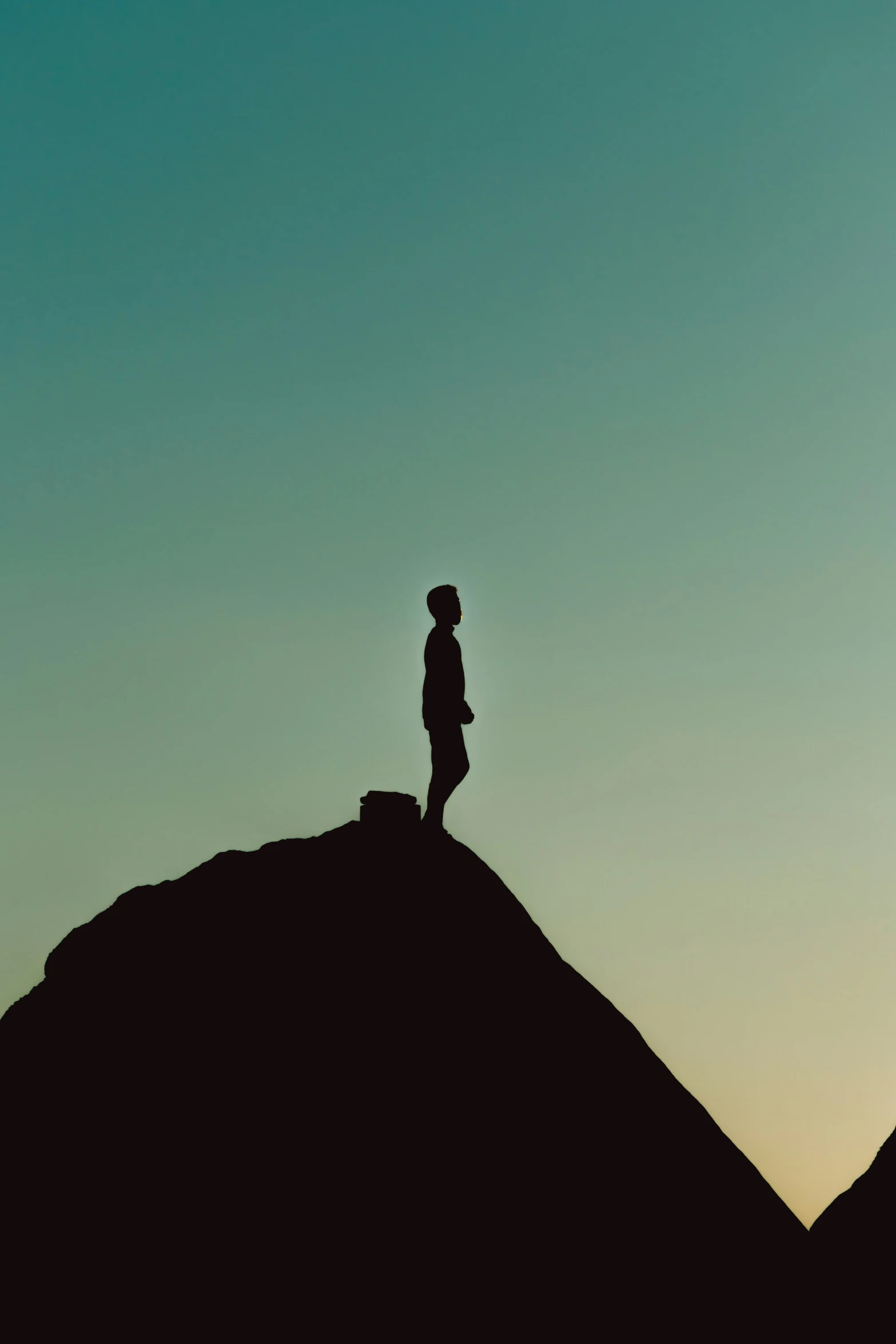 a silhouette of a person standing on top of a large rock