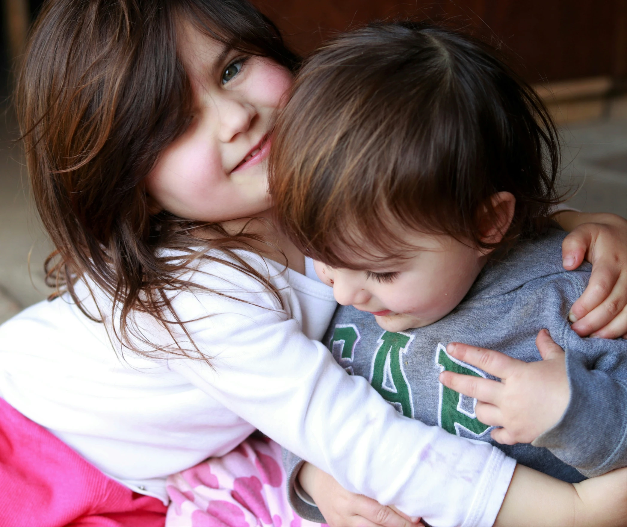 two girls sitting on the ground holding onto each other