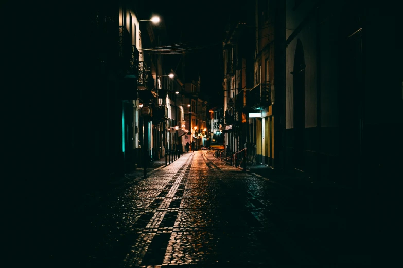 a small alley way at night with people walking down the sidewalk