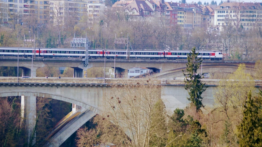 multiple passenger trains traveling on the same track over an elevated bridge