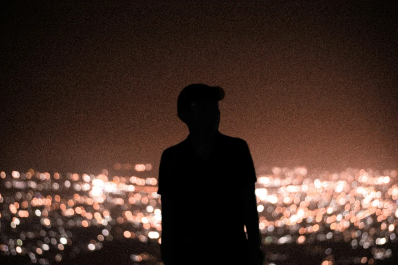 a man in dark jacket standing on top of a hill