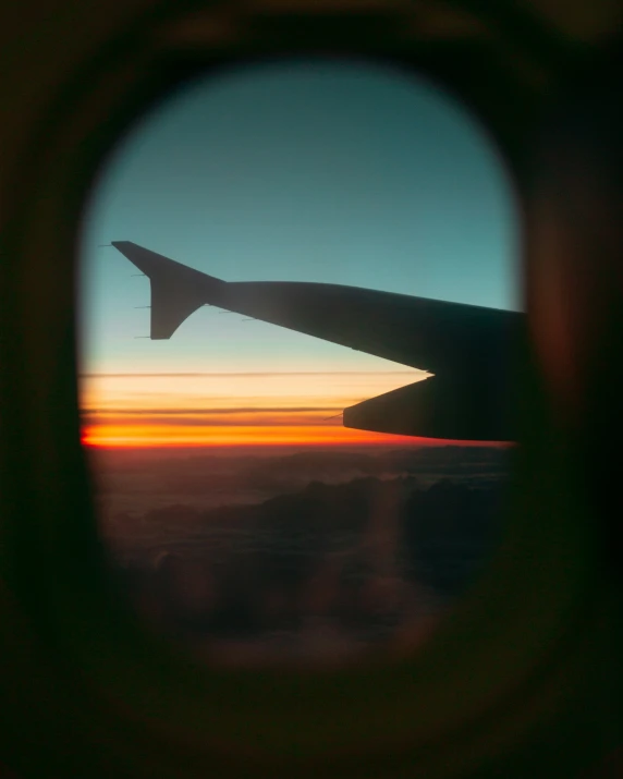 an airplane wing in the sky through a window