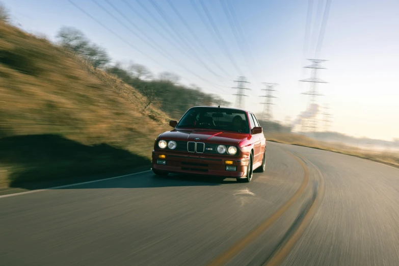 a red car is driving down a country road