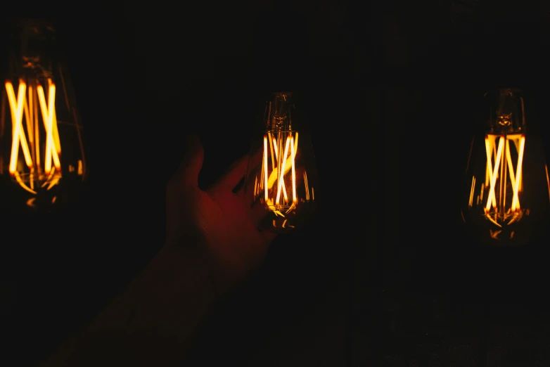 a person holding an orange light bulb up in the dark