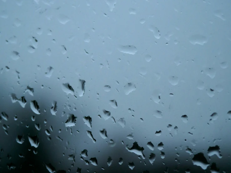 rain drops hang on the window as dark smoke rises in the background