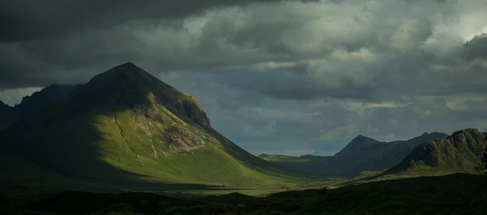 dark, storm - backed clouds cover a mountain range