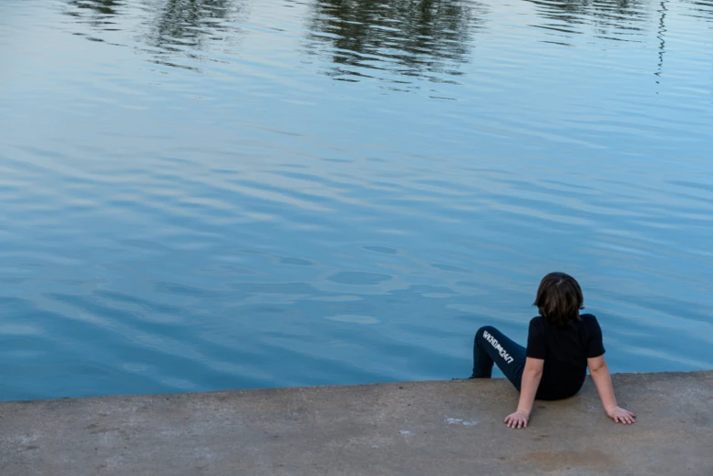 a person sitting on the edge of a body of water