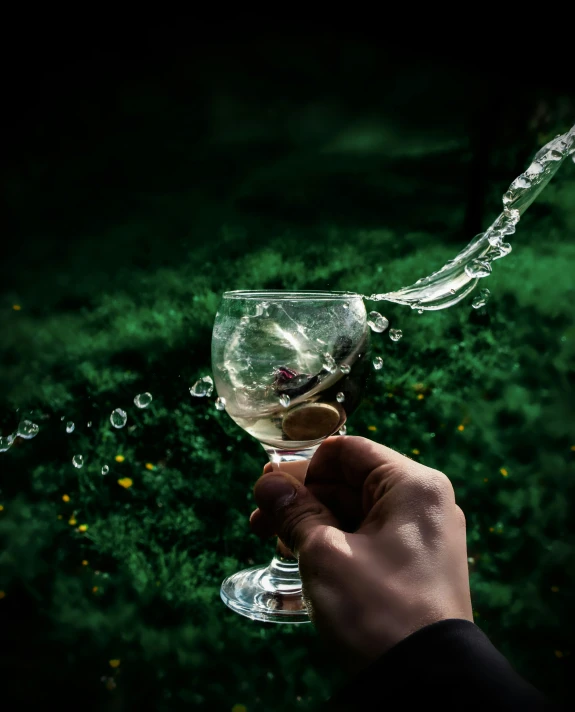 a person holding up a wine glass that has water flying out of it