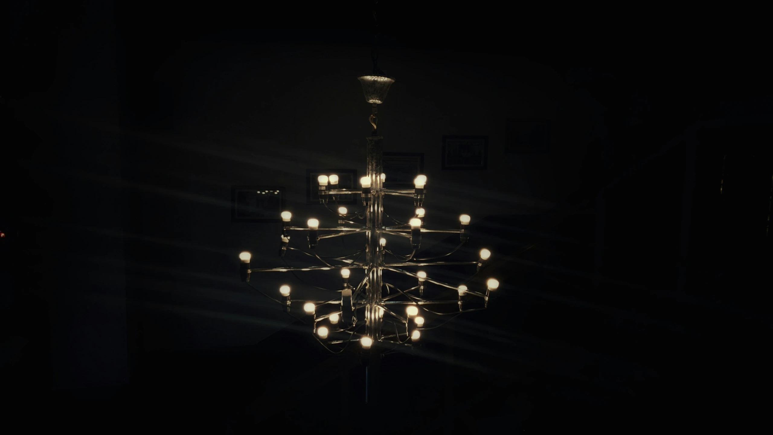 an artistic and unique chandelier is illuminated by small light bulbs