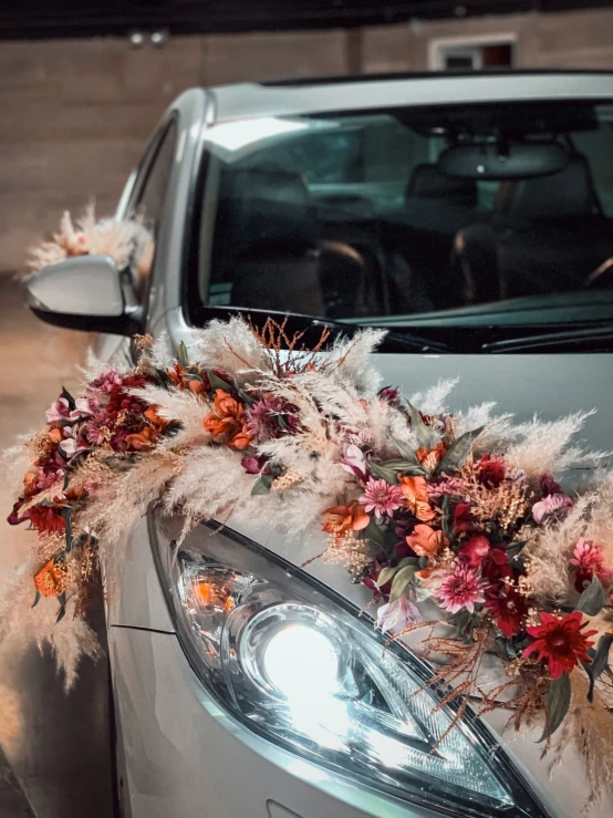 there is a car with flowers and feathers decoration on the front