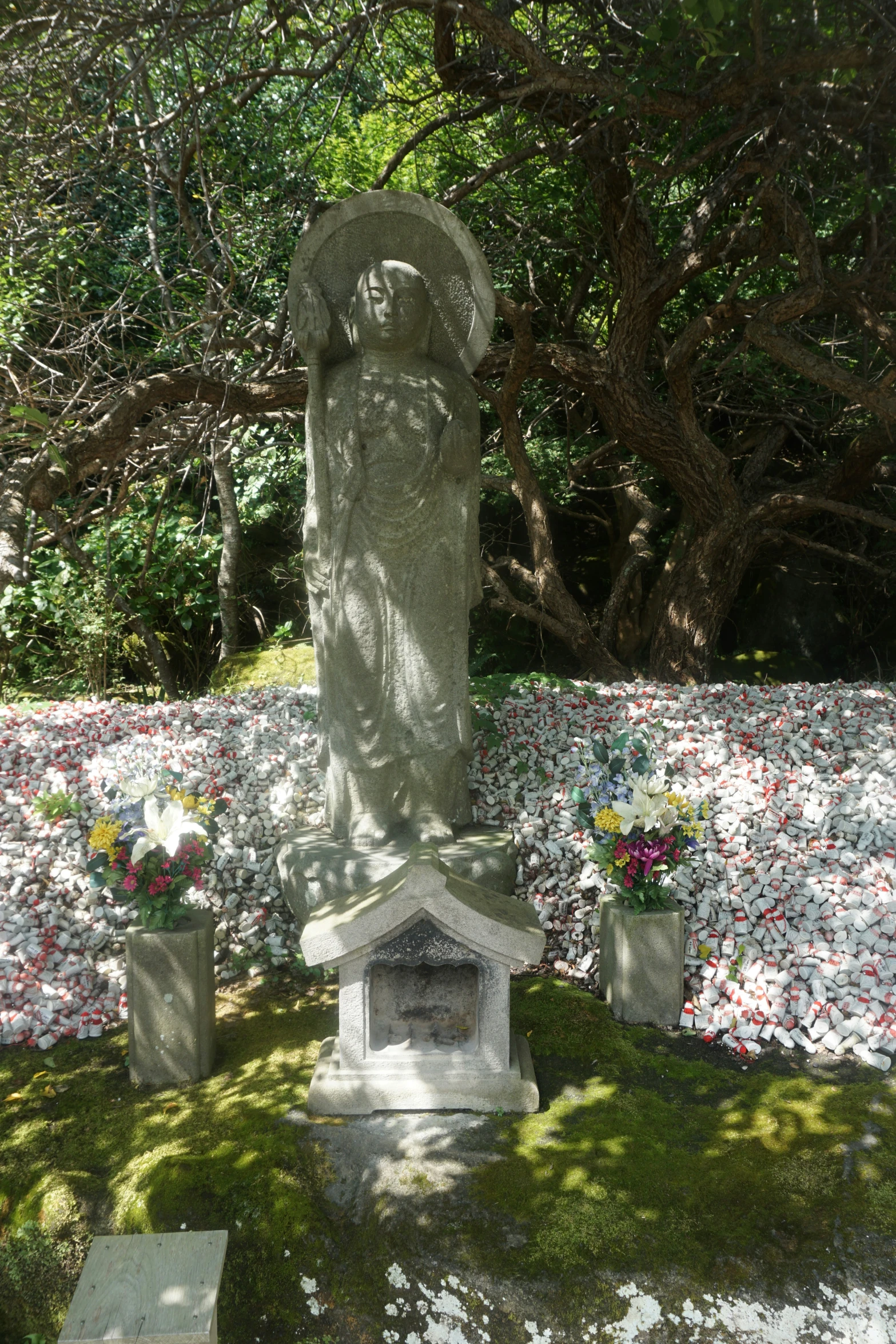 a stone statue in the middle of some flowers