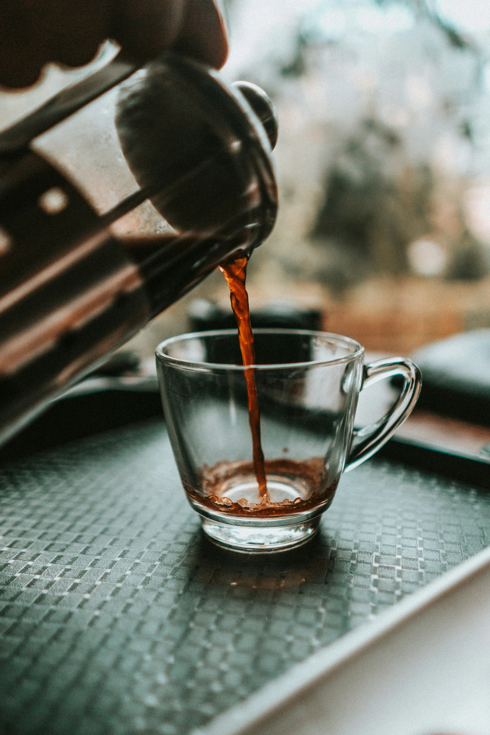 a person pours some tea into a glass cup