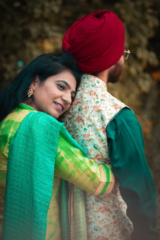 man hugging girl with bright colored shawl on her head