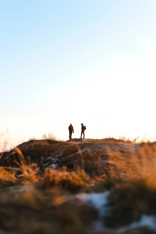 two people standing on top of a hill