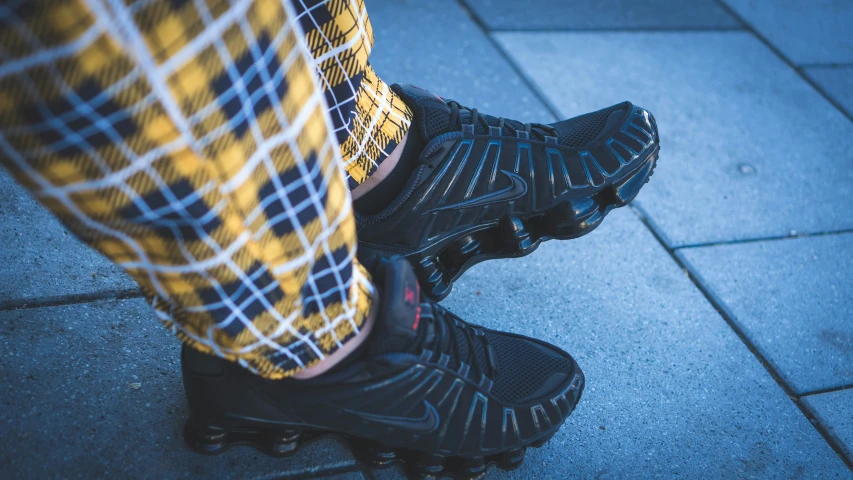 person's feet in sneakers standing on top of a skateboard