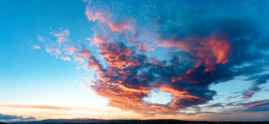 colorful cloud formation over small mountains at sunset