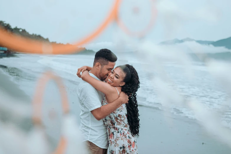a couple hugging on the beach by the water during their engagement session