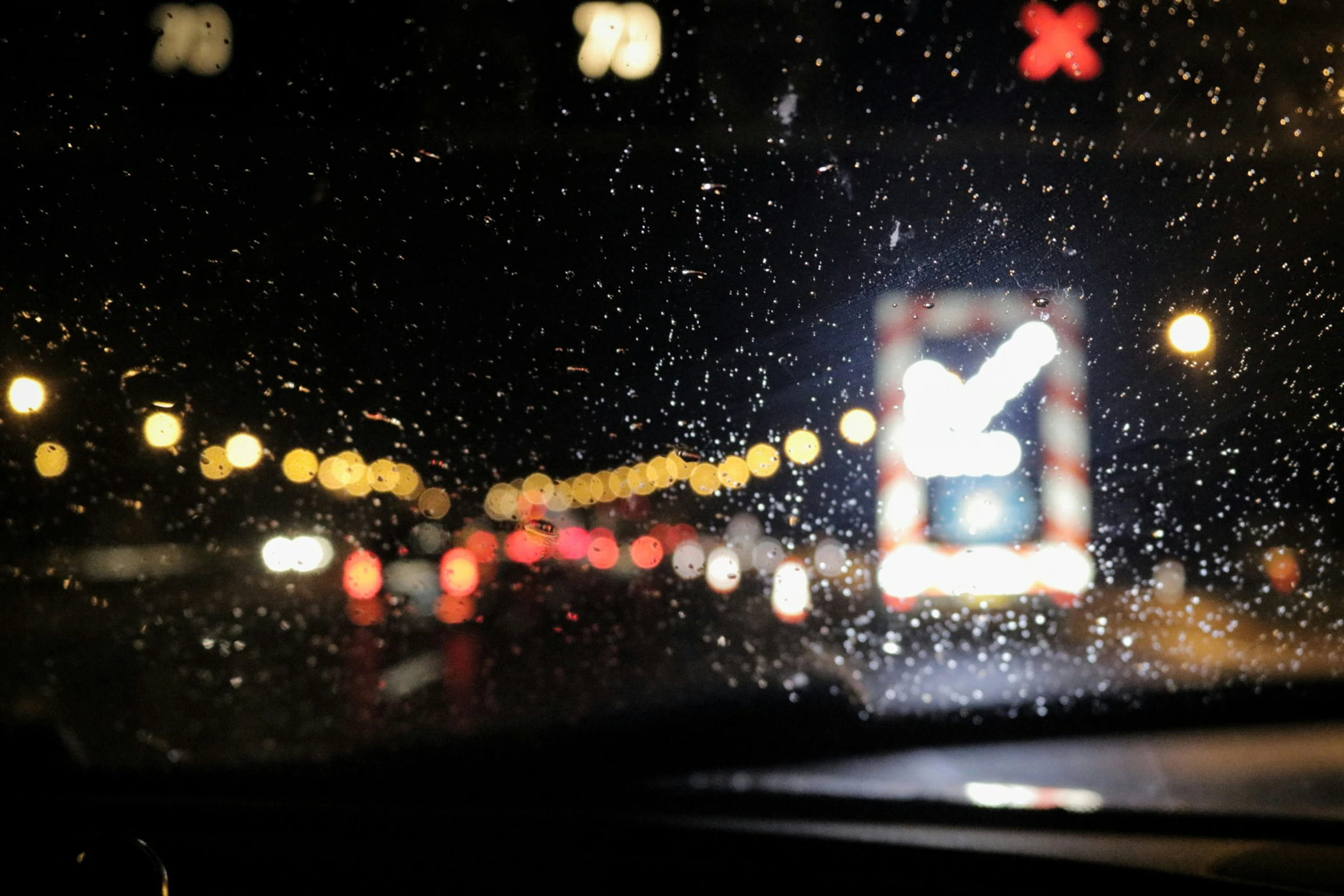 a wet windshield with the lights on at night