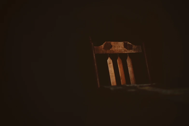 a wooden chair sitting in a dark room