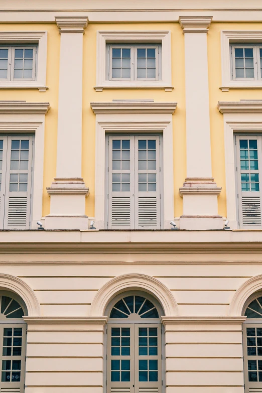 a yellow and white building with three different windows