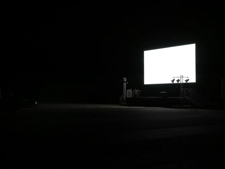 a person standing under a large screen in the dark