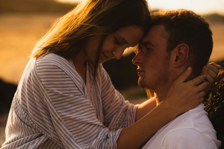 a man hugging a woman's chest as the sun is setting