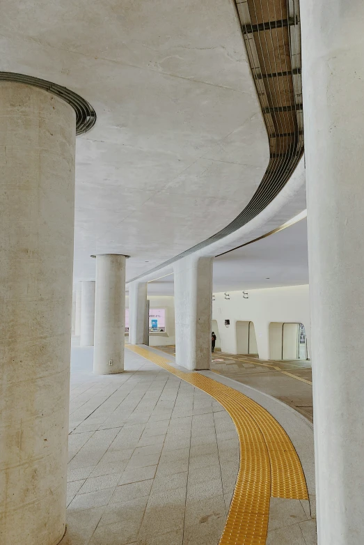 a long hallway with some light colored walkway in between two large pillars