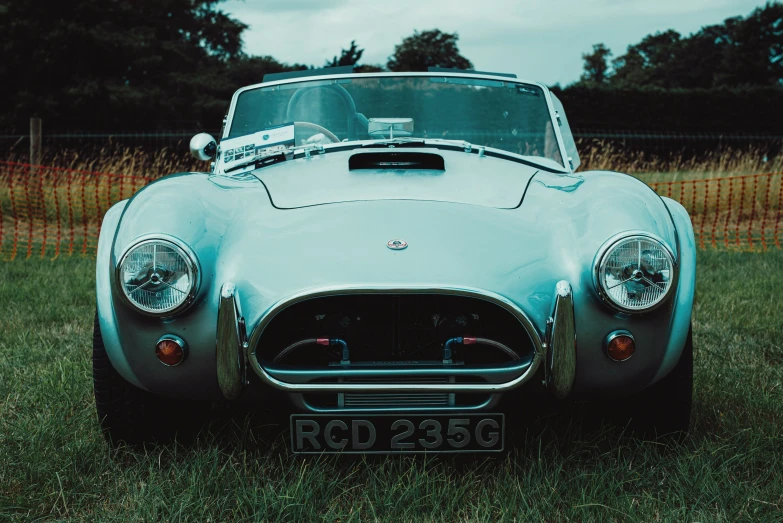 an antique sports car in the grass with the roof down