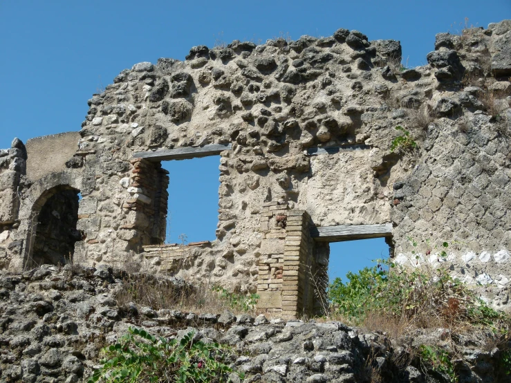 an old building with several open windows and mossy vegetation