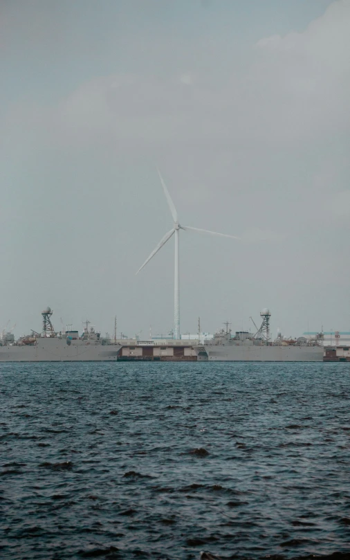 an old ship is on the water near a windmill