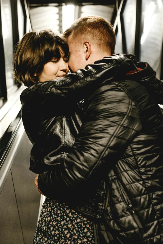 two people emcing each other by a wall