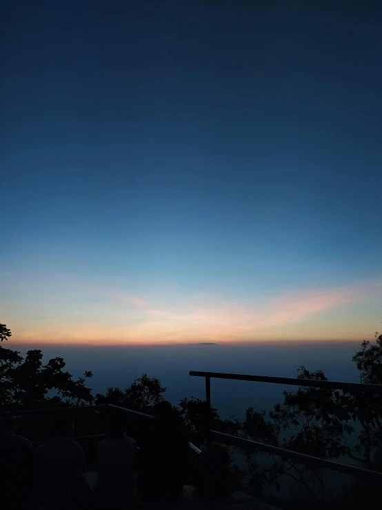 the silhouette of people watching the sunset on a hill