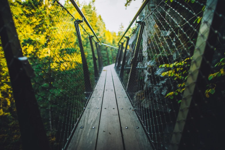 a wooden bridge with a wire fence going over it