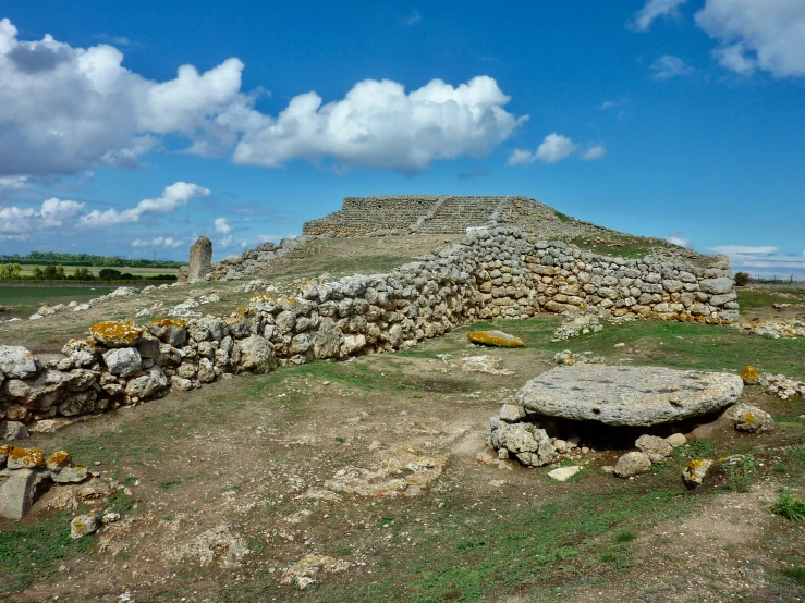 a stone well in the middle of a green field