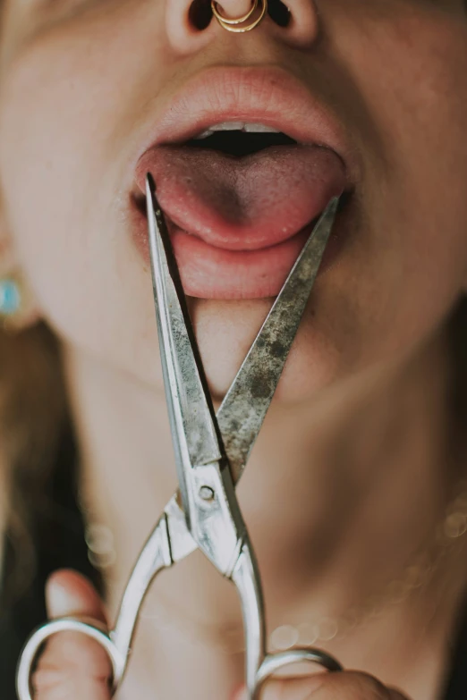 a woman holding a pair of scissors to her mouth