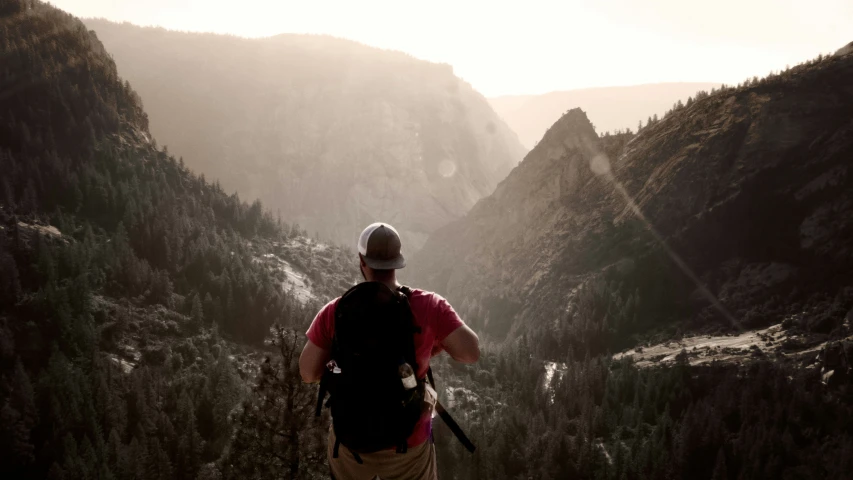 a man standing on top of a mountain next to the woods