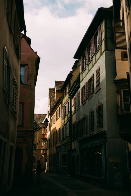 an alley between two old buildings on a cloudy day