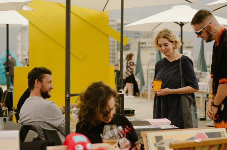 two women standing next to a man and others at an outdoor cafe