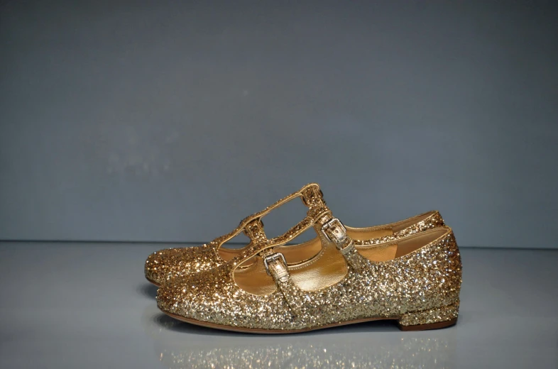 the gold children's shoes are shiny and shiny