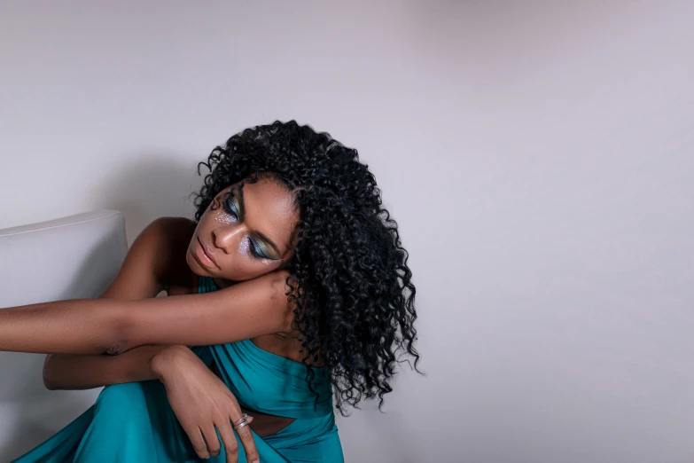 a black woman with a blue dress with green eyes looking down